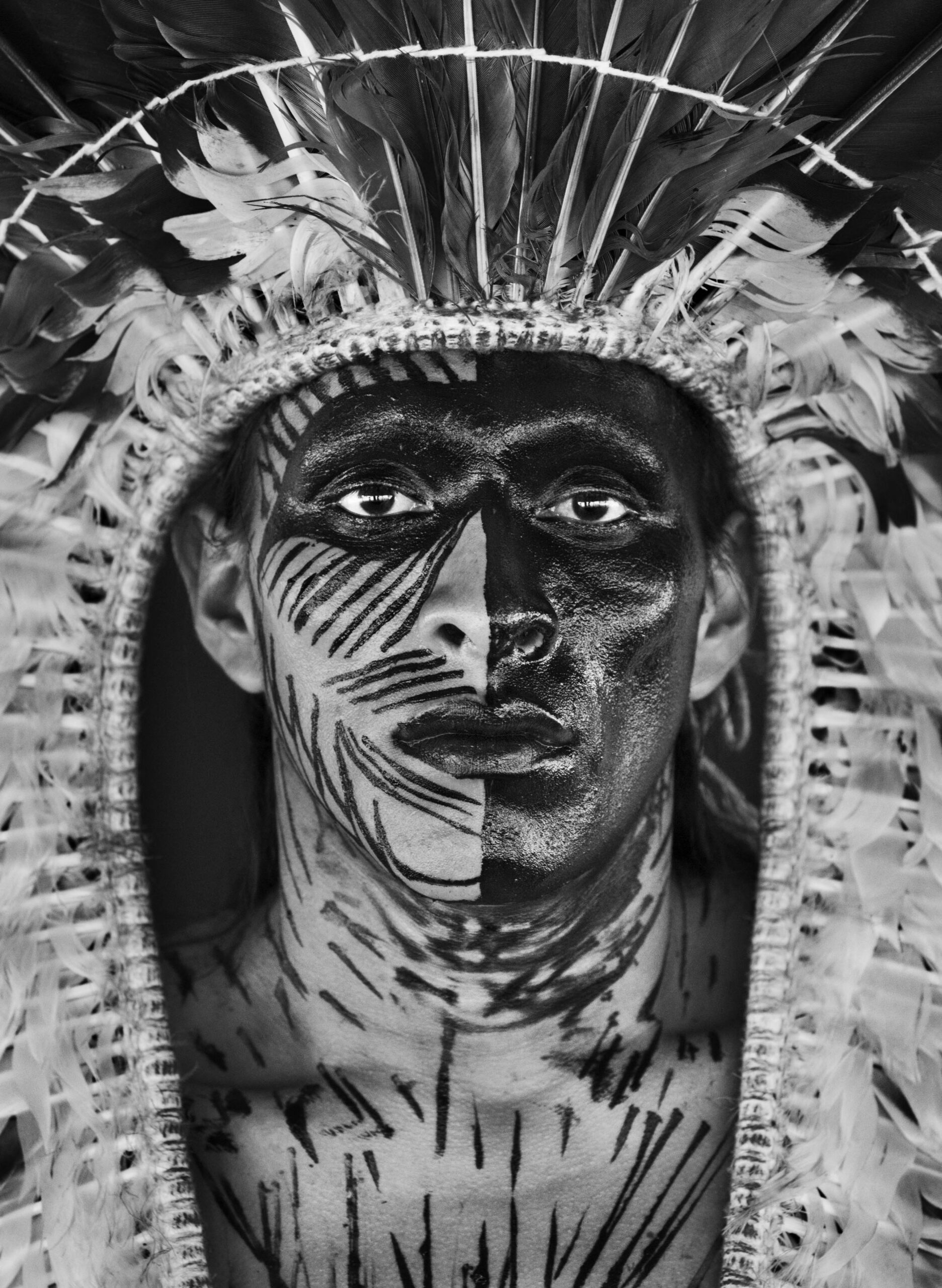 Eine Schwarz-Weiß-Fotografie des Fotografen Sebastião Salgado zeigt ein Porträt einer Person mit Gesichtsbemalung.