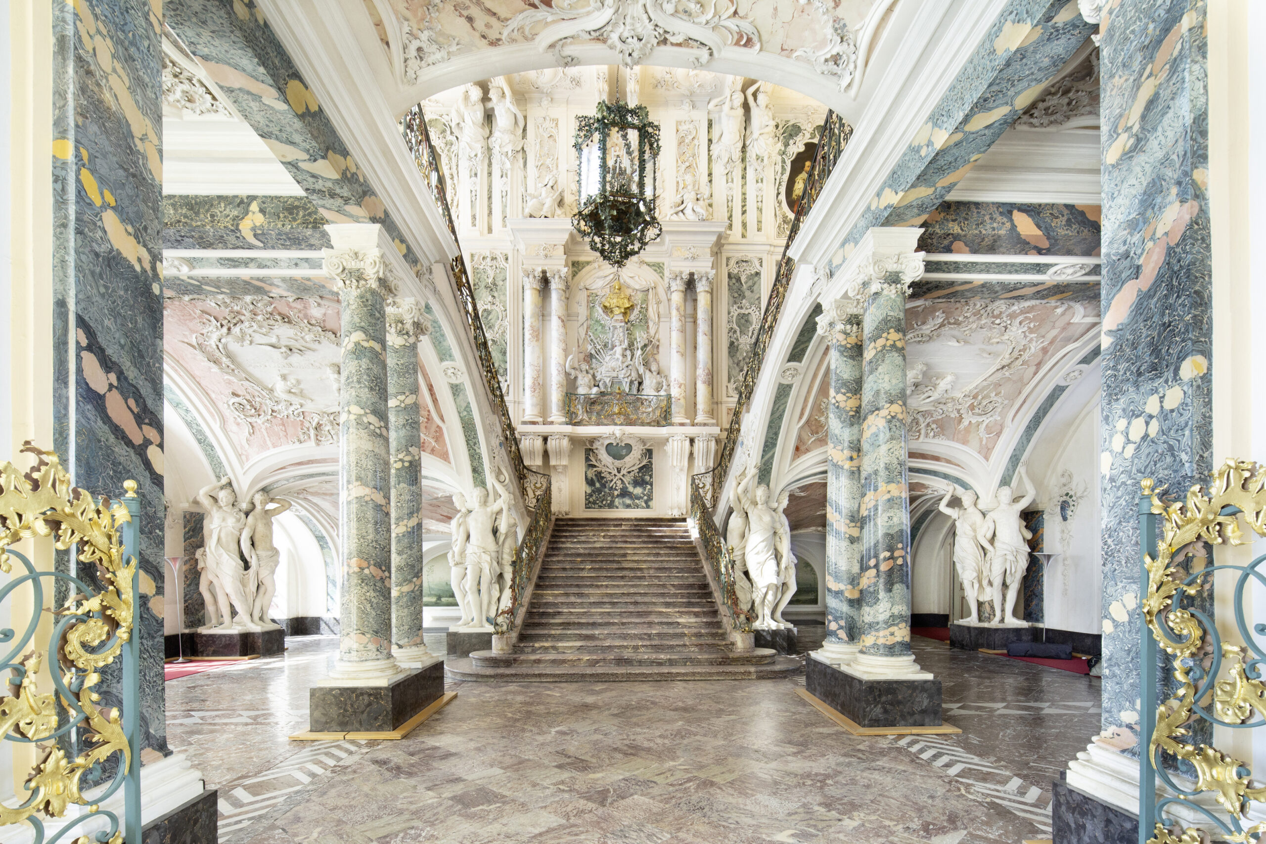Foto des prunkvoll gestalteten Treppenhauses in Schloss Augustusburg mit Blick auf den zentralen Treppenaufgang.